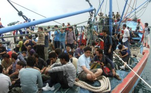 Asylum seekers sit on a fisherman's boat after they were rescued when their boat sunk off Sunda straits